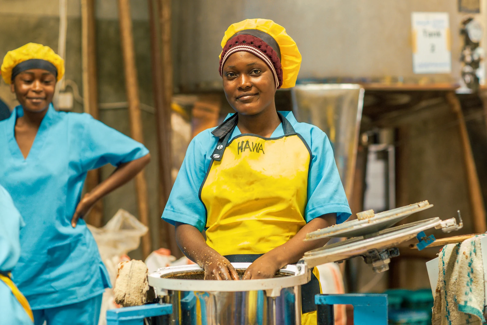 An Upendo processing team member smiling beside the equipment